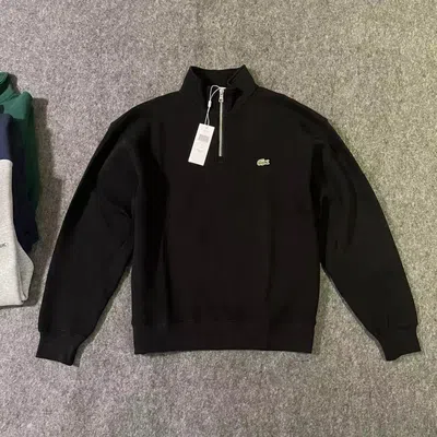 A black half-zip sweatshirt laid flat with the tag attached