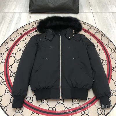 A black bomber jacket with a fur-trimmed hood photographed flat